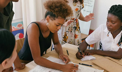 Un groupe de personnes concentrées autour d'une table, remplissant des documents avec attention, dans un cadre collaboratif et studieux.